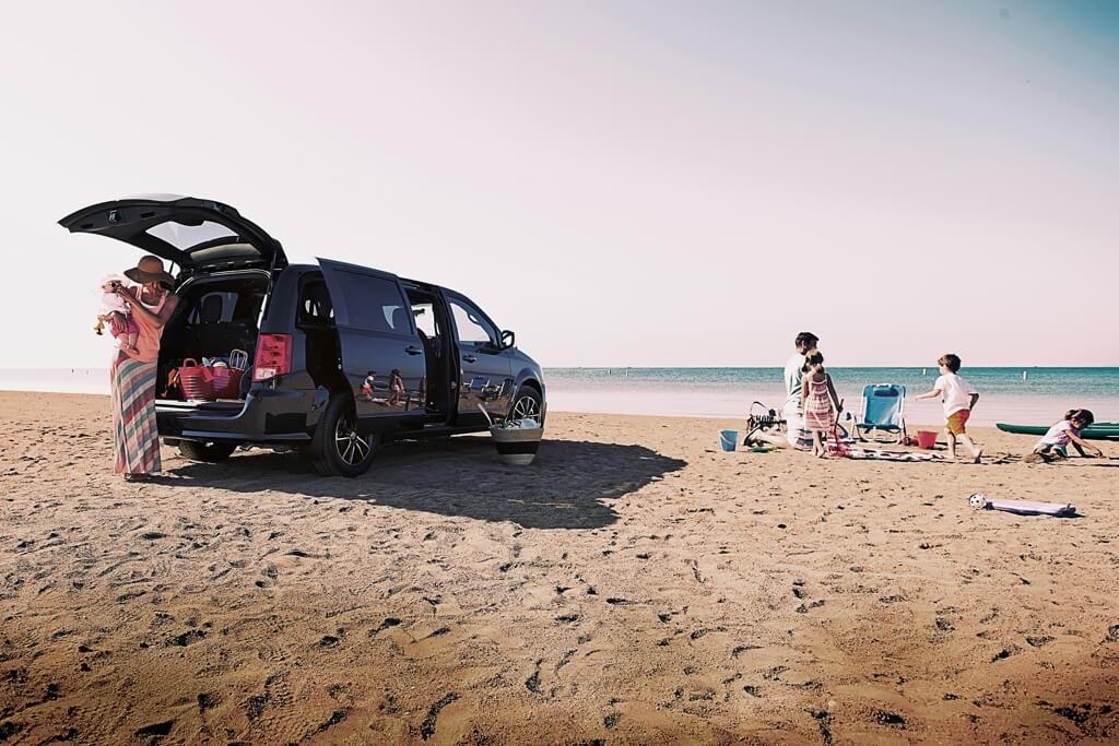 A family on a beach with the 2019 Dodge Grand Caravan.