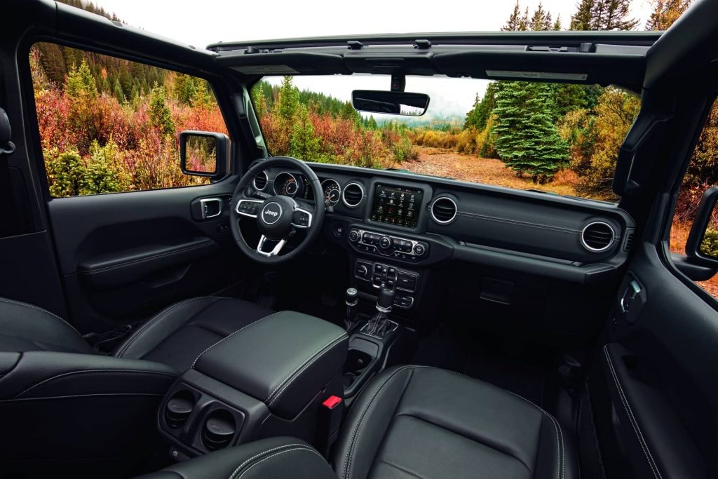 Intérieur du Jeep Wrangler 2020 incluant sièges chauffants de couleur noir et toutes ses autres commodités avec la vue d'extérieur dans une forêt pendant la saison d'automne