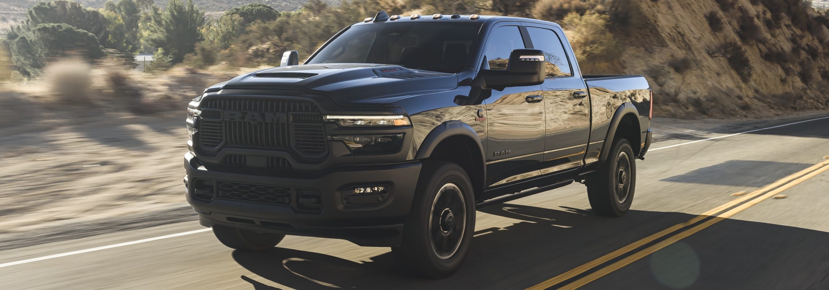 Ram 2500 2026 noir en mouvement sur une route de montagne, illustrant sa performance et sa stabilité à haute vitesse.