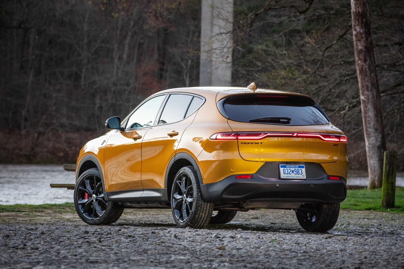 Vue arrière du Dodge Hornet GT 2025 jaune stationné près d’un lac sur sol rocailleux.