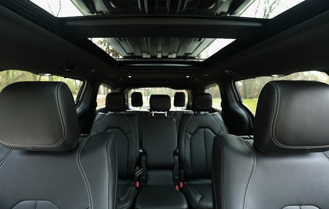 Habitacle du Chrysler Pacifica 2025 avec sièges en cuir noir et toit ouvrant panoramique, offrant confort et luxe aux passagers.