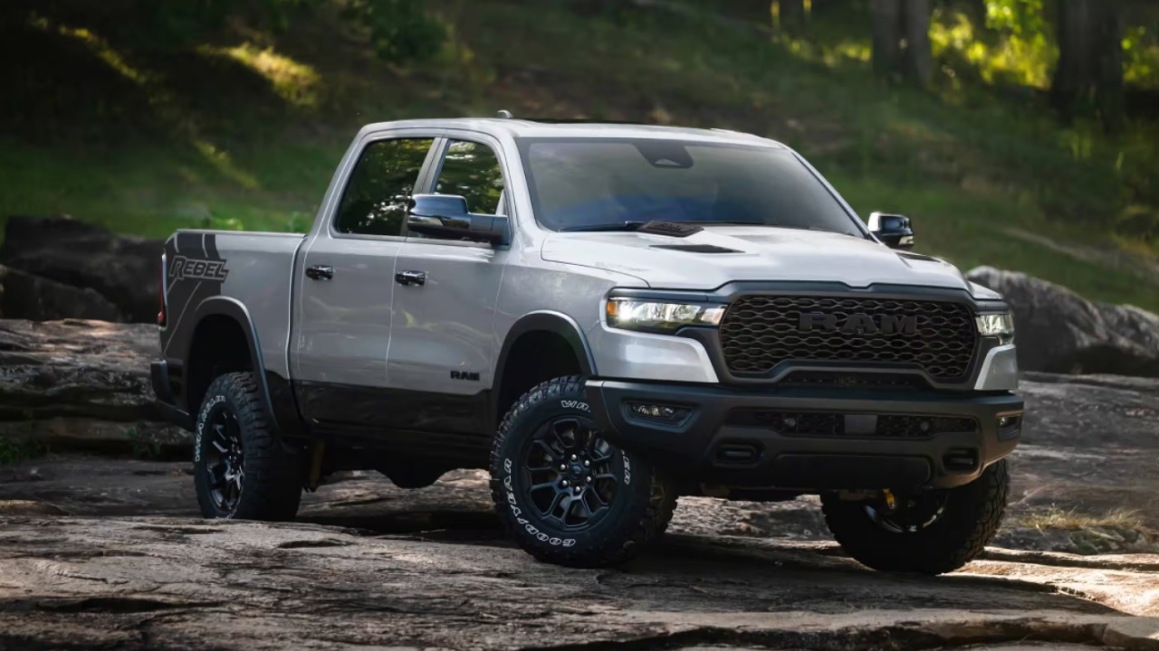 Ram 1500 Rebel 2026 gris sur terrain rocheux en forêt, soulignant ses capacités hors route robustes.