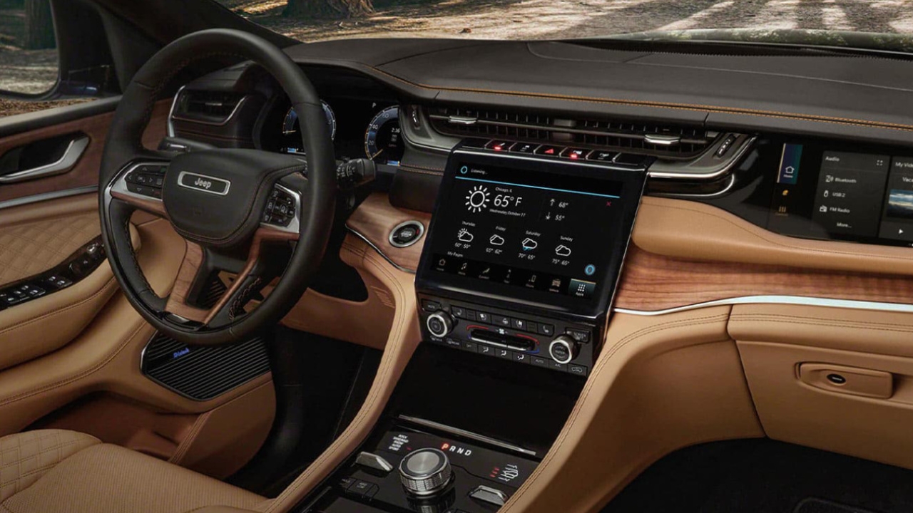 Tableau de bord du Jeep Cherokee 2026 avec écran tactile central et finitions bois, soulignant son design technologique et raffiné.