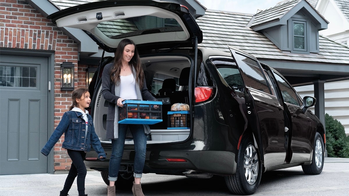 Une femme et son enfant qui décharge un Chrysler Grand Caravan 2025