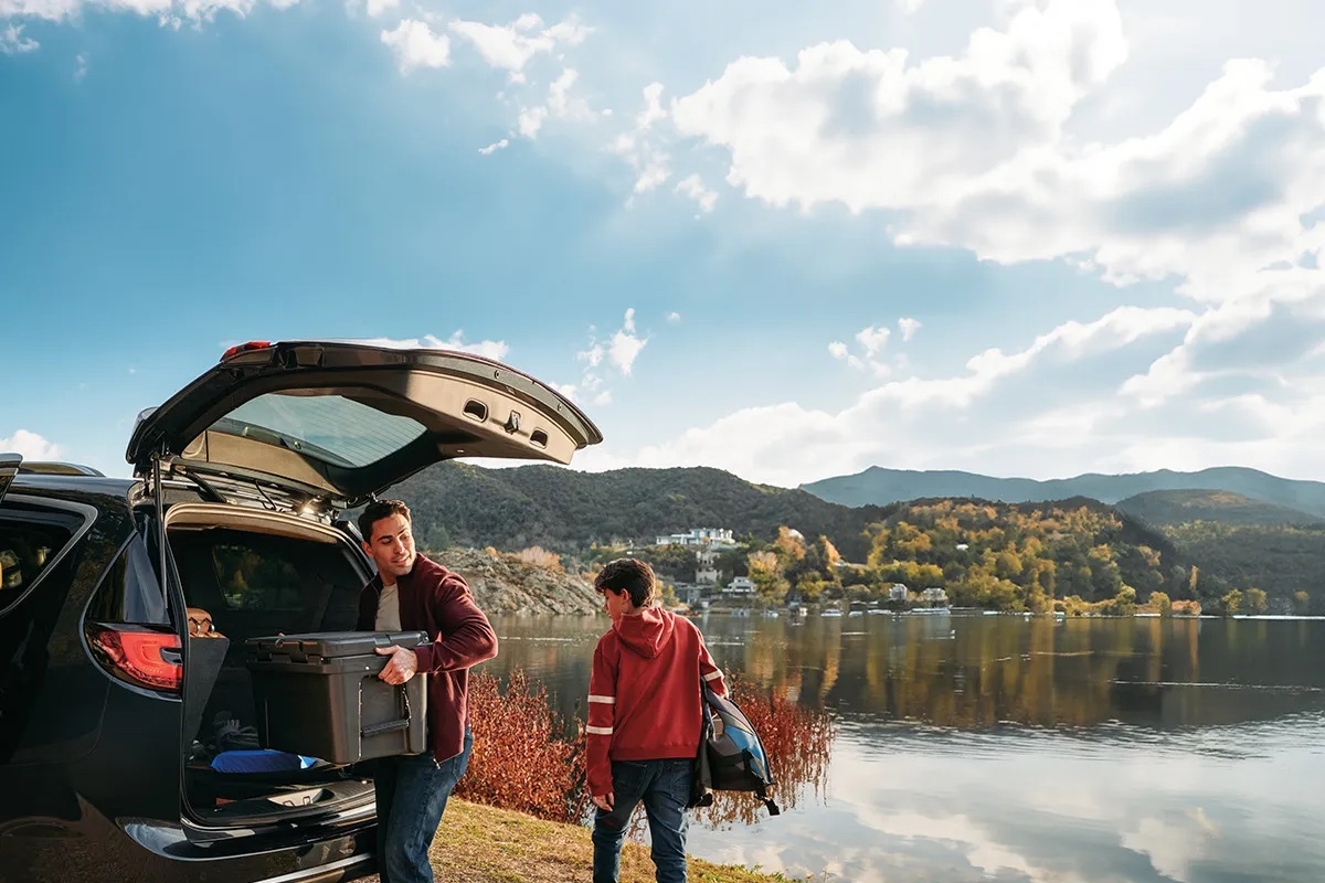 Famille déchargeant le coffre de la Chrysler Pacifica 2026 noir près d’un lac, soulignant l’espace et la praticité du minivan.