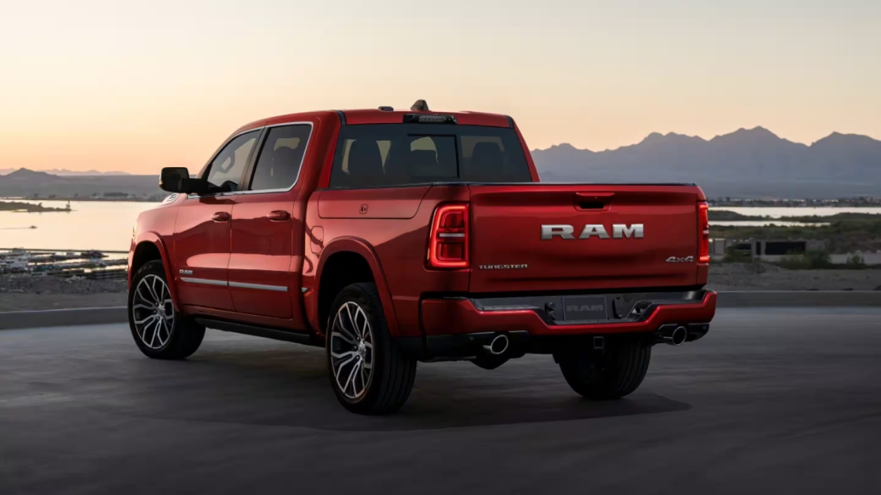 Ram 1500 2026 rouge vu de l’arrière au coucher du soleil, avec hayon affichant le logo RAM et doubles sorties d’échappement.