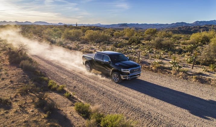 RAM 1500 Laramie Longhorn 2020 conduisant sur une route de sable avec des chaînes de montagnes au loin