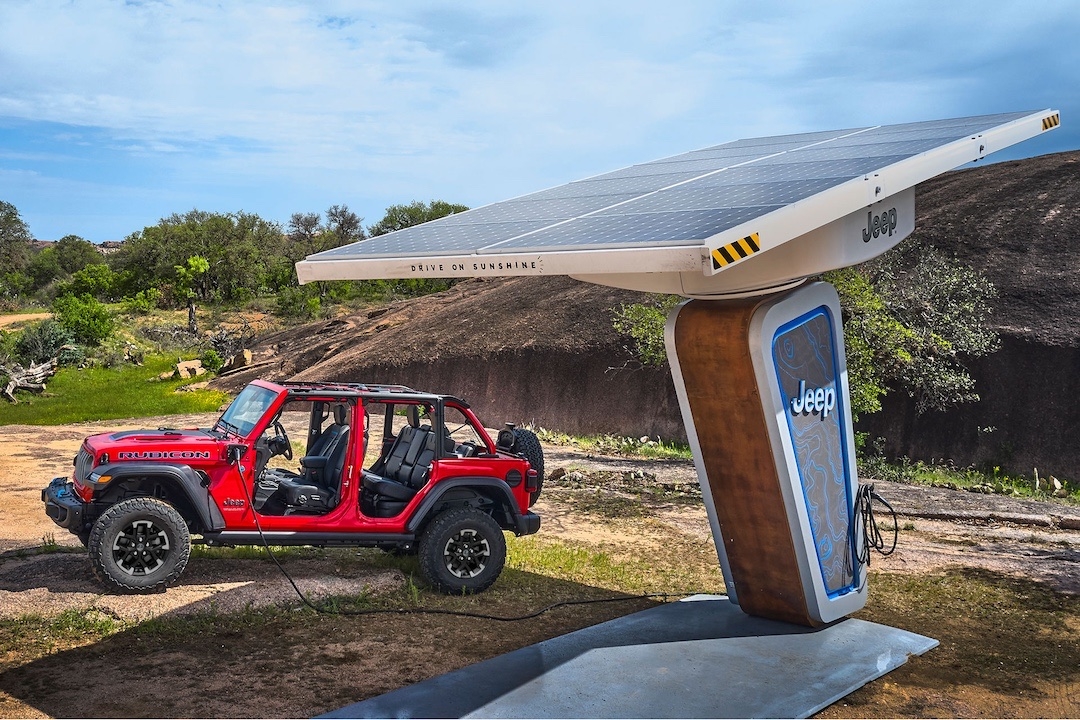Jeep Wrangler 4xe 2025 Rubicon rouge en recharge à une borne solaire Jeep en pleine nature.