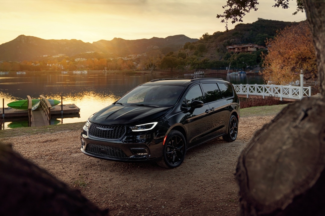 Chrysler Pacifica 2025 noir stationné près d’un lac au coucher du soleil, mettant en avant son style élégant et moderne.