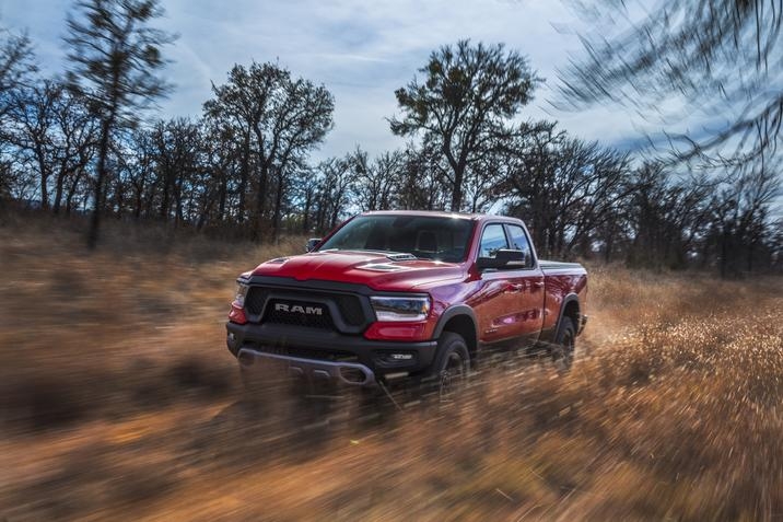 RAM 1500 Rebel 2020, design rouge, conduisant dans un champs d'herbe et quelques arbres autour