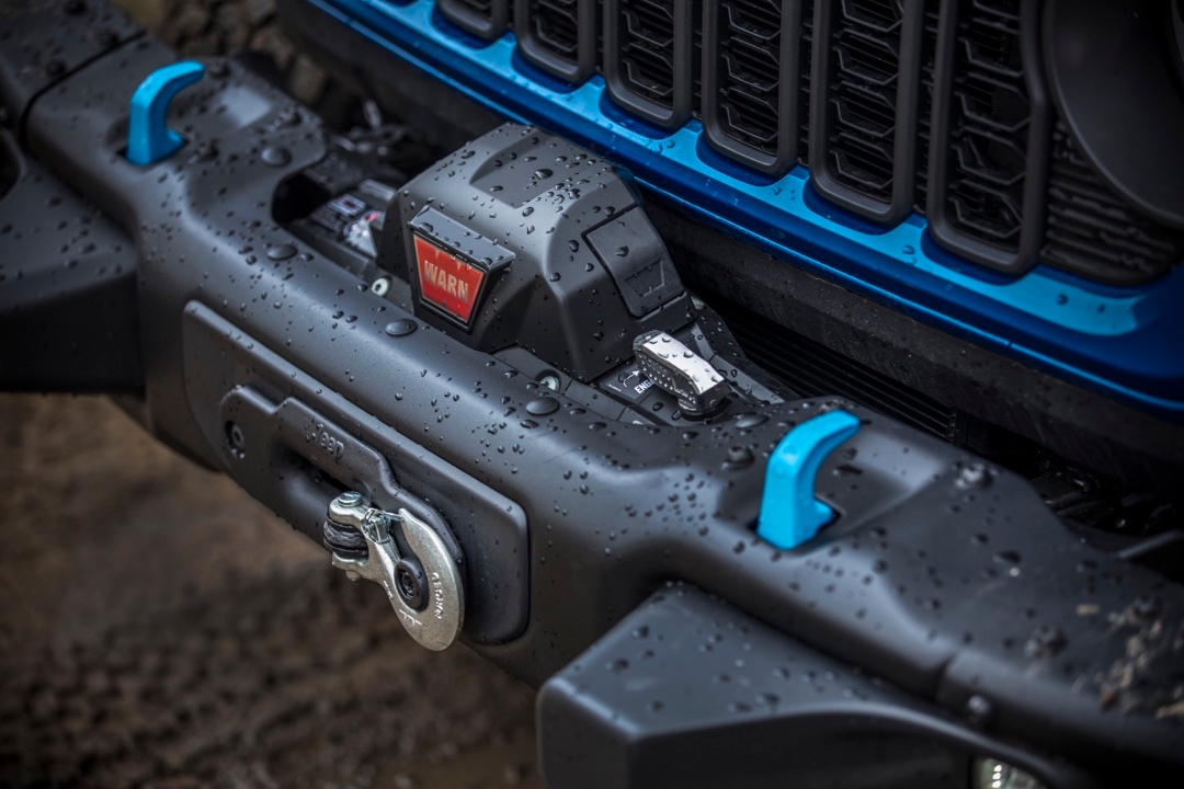 Gros plan sur le treuil WARN installé à l’avant du Jeep Wrangler 4xe 2025 Rubicon bleu, avec gouttes de pluie.
