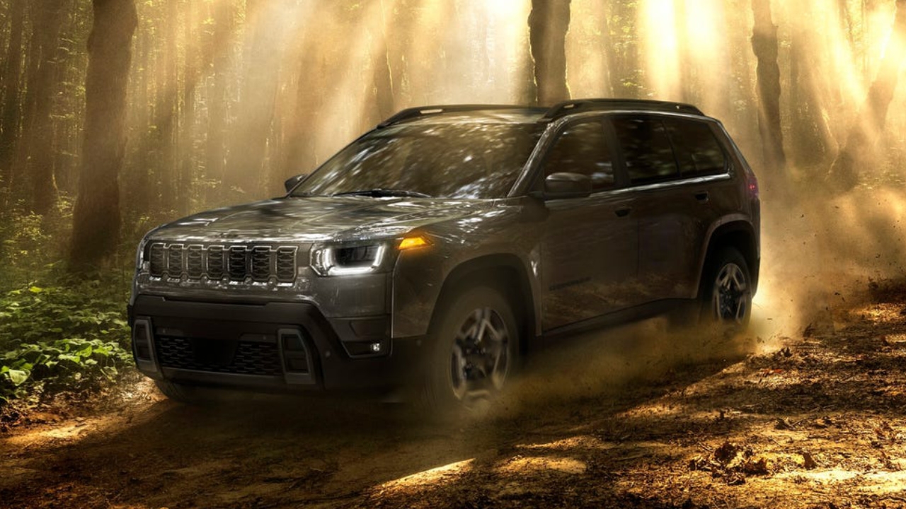 Jeep Cherokee 2026 gris en action sur un chemin forestier, démontrant ses capacités tout-terrain et sa robustesse.